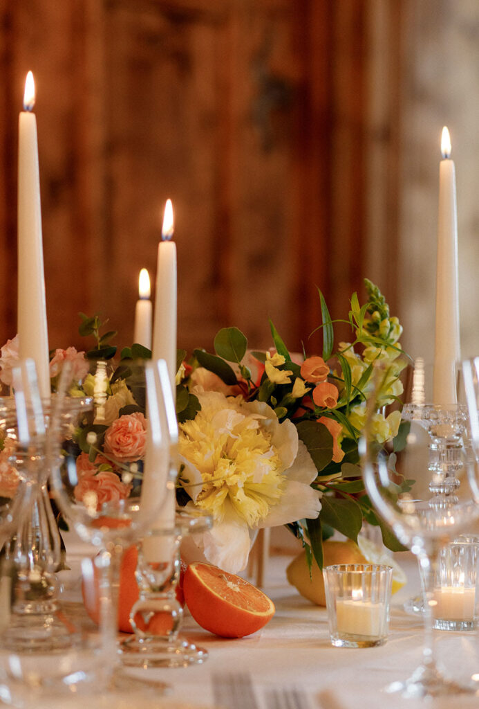 Decorazione floreale dei tavoli con peonie rose candele e agrumi