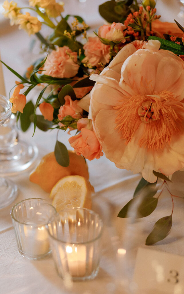 Decorazione floreale dei tavoli con peonie rose candele e agrumi